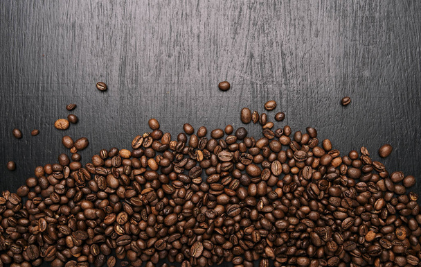 γκρο πλαν θέα φρυγμένους κόκκους αρωματικό καφέ σε μαύρο ξύλινη επιφάνεια - Φωτογραφία, εικόνα