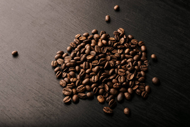 top view of roasted aromatic coffee beans on black wooden table  - Photo, Image
