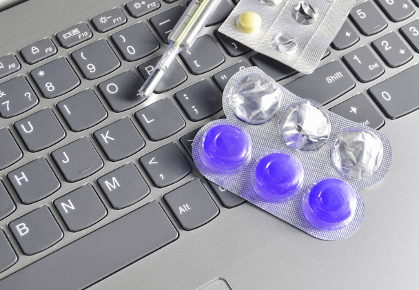Blistry tabletek, termometr na laptop klawiatura szary. Pojęcie medyczne, góry vie - Zdjęcie, obraz