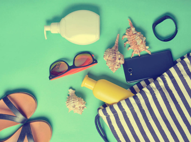 Strandtasche und Accessoires zum Entspannen am Strand auf blauem Pastellhintergrund. das Konzept des Seebades, Sommerzeit. Draufsicht, flach, minimalistisch - Foto, Bild