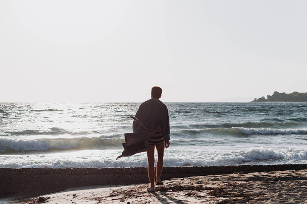 Młodego mężczyznę w szlafroku, na plaży w zachód słońca - Zdjęcie, obraz