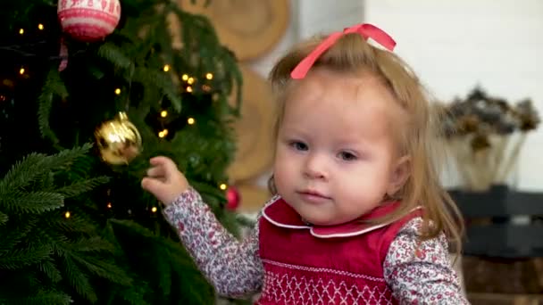 Μικρό κορίτσι διακόσμηση το χριστουγεννιάτικο δέντρο. Μικρό κορίτσι παίζει με το παιχνίδι στο χριστουγεννιάτικο δέντρο. - Πλάνα, βίντεο