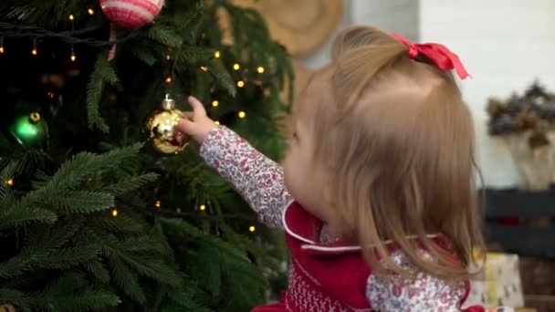 Маленькая девочка украшает елку. Девочка играет с игрушкой на елке
 - Кадры, видео