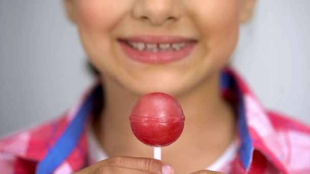 Teenage girl showing lollipop at camera, dental care concept sugar causes caries - Foto, imagen