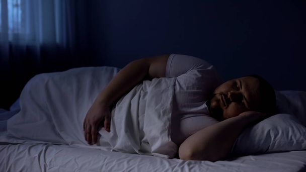 小太りの男がベッドで寝て、夜快適なマットレス、残りの部分の上でリラックス - 写真・画像