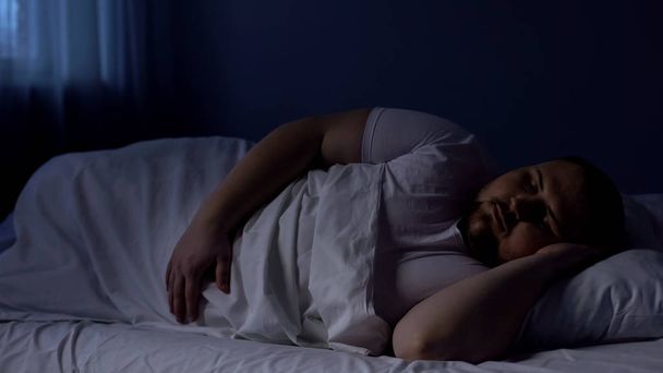 Obese man sleeping in bed, relaxing at night on comfortable mattress, rest - Foto, Bild