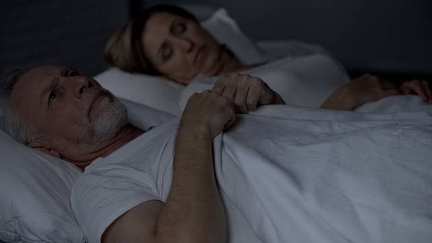 Senior man lying in bed having hard thoughts, unfaithful relations, troubles - Foto, Imagem