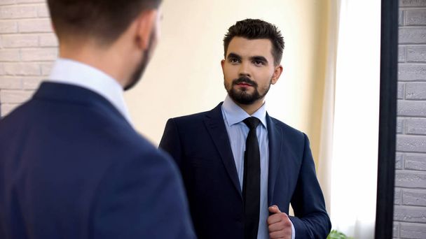 Businessman is suit looking in mirror before important meeting, checking outfit - Foto, Bild