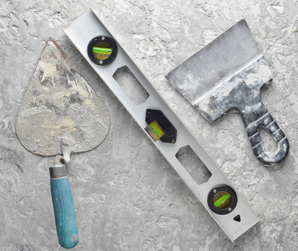 Building tools on a gray concrete background. Spatula, trowel, level, level, top vie - Foto, Bild