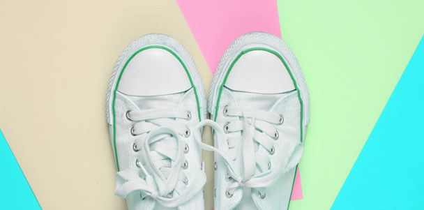 Παλιά ρετρό αθλητικά παπούτσια με λευκά κορδόνια σε χρωματιστά παστέλ φόντο. Μινιμαλισμός. Κορυφή Vie - Φωτογραφία, εικόνα