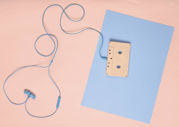 Audio cassette en koptelefoon op een blauwe pastel roze achtergrond. Muzikale liefde concept. Retro-stijl. Minimalisme. Top Vie - Foto, afbeelding