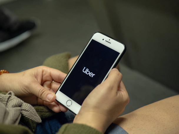 Woman uses Uber mobile app on iPhone while commuting on subway train - Foto, imagen