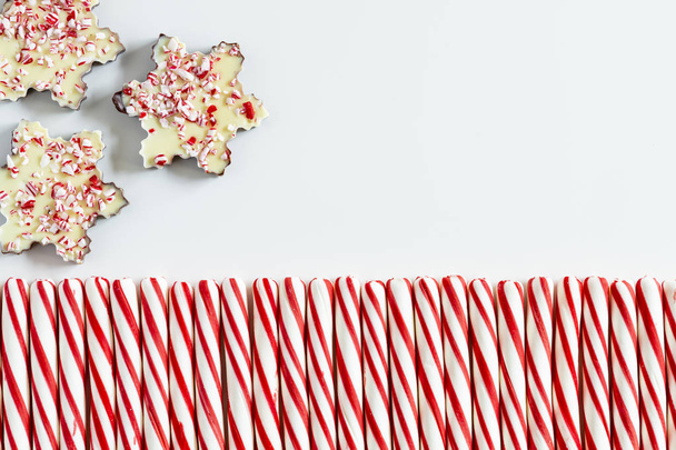 Close up of background of three chocolate peppermint bark snowflakes with row of red and white striped peppermint candies and blank space for text - Foto, Bild