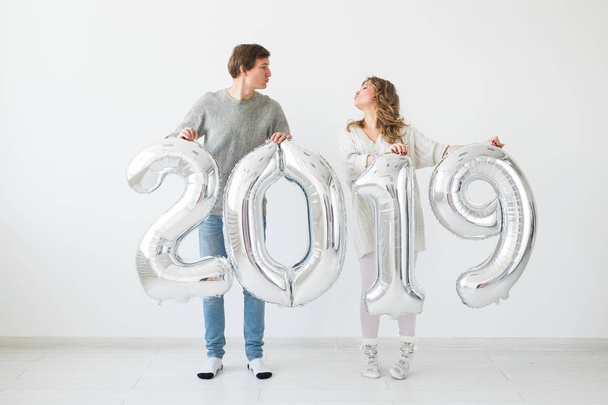 New 2019 Year is coming concept - Cheerful young man and woman are holding silver colored numbers - Foto, afbeelding
