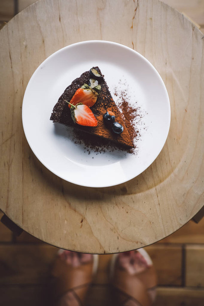 Una rebanada de pastel de chocolate crudo vegano en la mesa de madera desde arriba. Sin azúcar, sin trigo, sin lácteos, postre sin harina. Foto de comida. Comida saludable, copyspace
. - Foto, Imagen