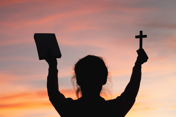Femme avec croix et bible dans les mains priant pour la bénédiction de Dieu le matin, la spiritualité et la religion
 - Photo, image