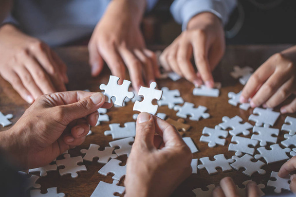 Hands of diverse people assembling jigsaw puzzle, team put pieces together searching for right match, help support in teamwork to find common solution concept, top close up view - Foto, imagen