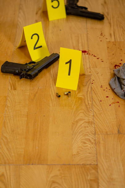 Bullet casings and gun next to markers at crime scene - Foto, afbeelding