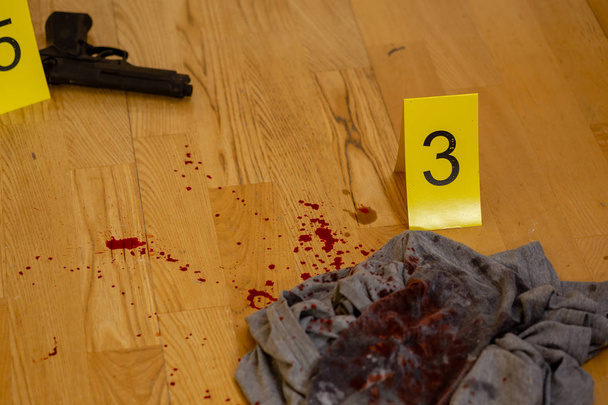 Bullets and gun next to markers at crime scene - Foto, afbeelding
