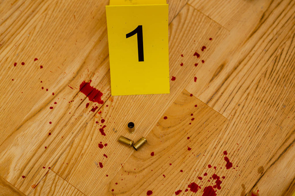 9 mm bullet casings next to crime scene marker and blood splatter - Foto, afbeelding