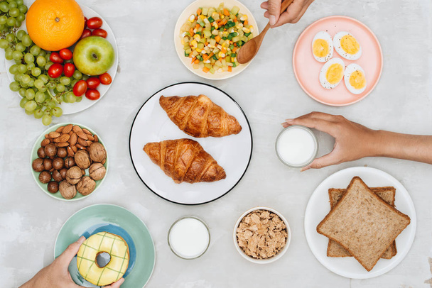 Ingredientes saudáveis de café da manhã em mesa cinza com mãos humanas
 - Foto, Imagem