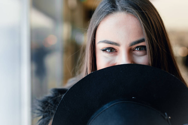 Pretty girl stand on the street wear black hat, look at window store and make funny expressions on her face. - Image - 写真・画像
