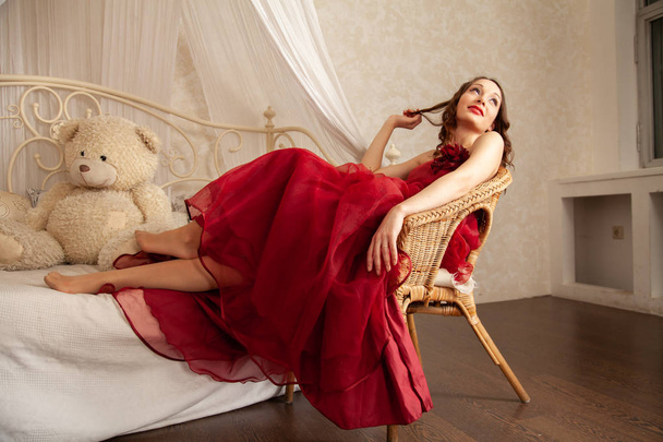 charmante meisje in een mooie avond lange jurk op de achtergrond van een hemelbed in haar slaapkamer - Foto, afbeelding