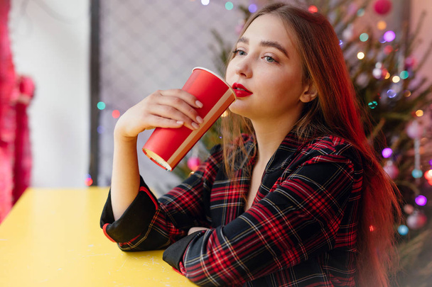 Mujer beber su café caliente mientras está sentado en el café. Retrato de mujer sonriente con estilo en ropa de invierno bebiendo café caliente. Estilo Invierno Femenino. - Imagen
 - Foto, Imagen