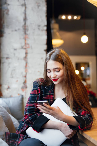 Femme travaille au café sur son ordinateur portable. Portrait de femme souriante élégante dans les vêtements d'hiver et le travail à l'ordinateur portable. Style d'hiver féminin. - Image
 - Photo, image
