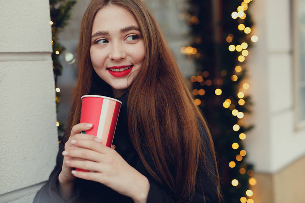 Vrouw haar hete koffie drinken tijdens het lopen op straat. Portret van stijlvolle lachende vrouw In de Winter kleding warme koffie drinken. Vrouwelijke stijl van de Winter. -Image - Foto, afbeelding