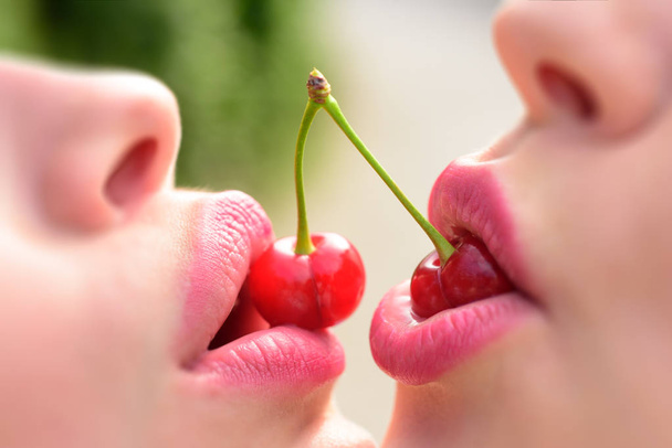 lesbisches Paar küsst Lippen. sexy lesbische Liebhaber Vorspiel. Kirsche und Versuchung. zwei Früchte für zwei Frauen. Weibliche Münder in Großaufnahme - Foto, Bild