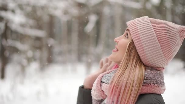 Mujer hermosa feliz en estilo casual rodando con las manos arriba mientras está nevando en la bonita plaza de la ciudad en el tiempo de invierno. Al aire libre. Retrato plano
 - Metraje, vídeo
