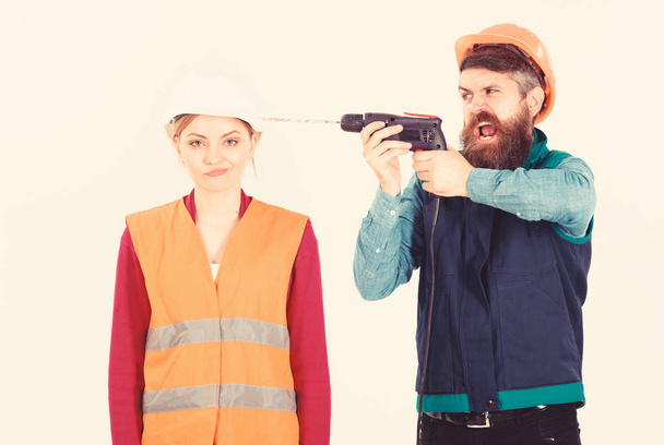 Annoying repair concept. Man with drill drills head of woman, white background. Husband annoyed wife. Woman with bored face in helmet, hard hat. Builder, repairman makes hole in female head. - Fotoğraf, Görsel
