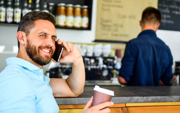 Coffee take away option for busy people. Man mobile conversation cafe barista background. Drink coffee while waiting. Glad to hear you. Man smartphone order coffee in cafe. Coffee break concept - Foto, Imagen