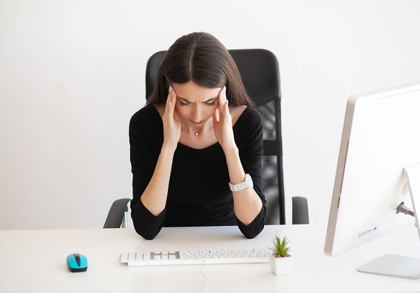 Dolor de cabeza. Mujer joven agotada sintiendo dolor en la cabeza después de trabajar en la computadora. Concepto de trabajo excesivo
 - Foto, Imagen