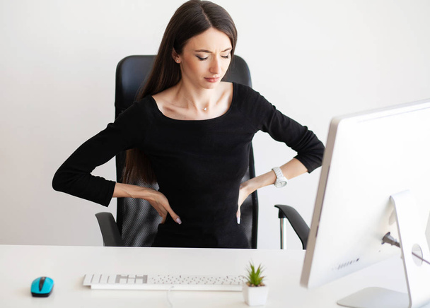 Back pain. Businesswoman sit in her office and feels pain in back - Фото, зображення