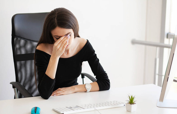 Kopfschmerzen. Erschöpfte junge Frau, die nach der Arbeit am Computer Kopfschmerzen verspürt. Überarbeitungskonzept - Foto, Bild