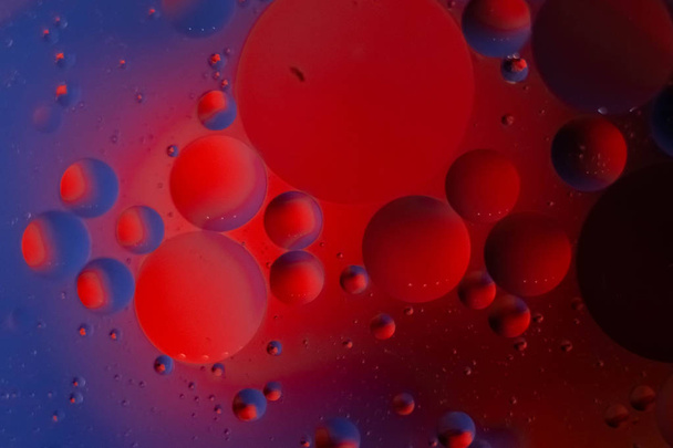 olie druppels in blauw en rood in een glas water, genomen macro Cup - Foto, afbeelding