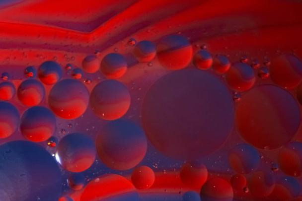 oil drops in blue and red in a glass Cup of water,taken macro - Foto, afbeelding