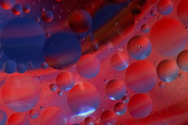 oil drops in blue and red in a glass Cup of water,taken macro - Photo, Image