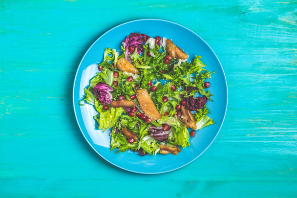 Friss egészséges saláta saláta, csirke és gránátalma kék lemez. Felülnézet, másol hely.  - Fotó, kép
