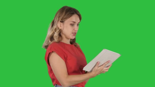 Medium shot. Side view. Woman in red t-shirt using tablet on a Green Screen, Chroma Key. Professional shot in 4K resolution. 006. You can use it e.g. in your commercial video, business, presentation - Кадры, видео