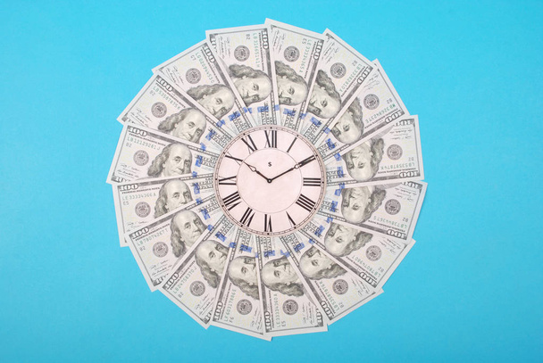 Concept van klok en dollar. Klok op mandala caleidoscoop van geld. Abstracte geld achtergrond raster patroon Herhaal mandala cirkel. Op blauwe achtergrond. - Foto, afbeelding