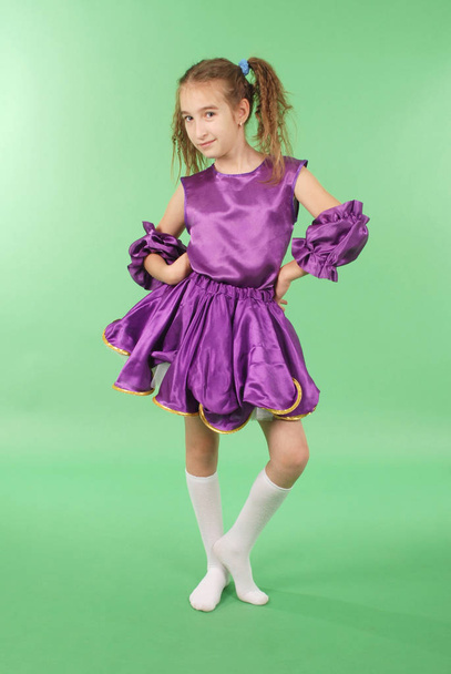 Jolie fille posant pour la caméra, dans une robe courte violette. Isolé sur vert
. - Photo, image