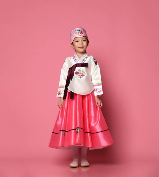 Korean little baby girl in traditional silk dress for new year celebration on pink with hands spread - Foto, Imagen