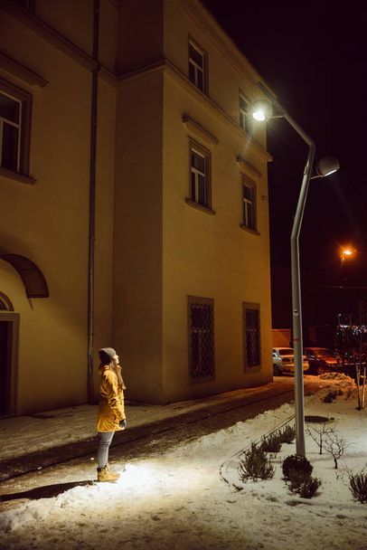 giovane donna adulta guardando il lampione della città durante la notte d'inverno. stile di vita
 - Foto, immagini