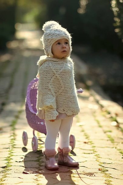 Toddler in knitted clothes playing outdoors - Фото, зображення