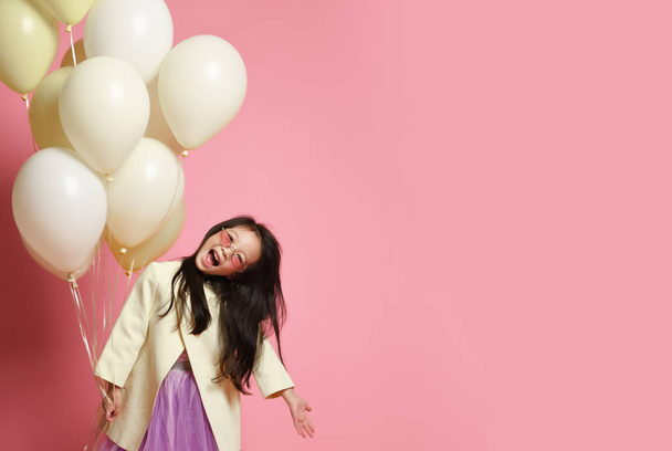 Little Korean baby girl in yellow fashion jacket and purple dress with balloons celebrate happy smiling screaming - Foto, imagen