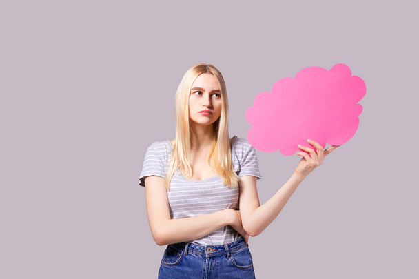 Young beautiful woman wearing white t-shirt and mom jeans, holding blank speech bubble with copy space for text. Attractive blonde female with empty message box. Grey isolated background. - Φωτογραφία, εικόνα