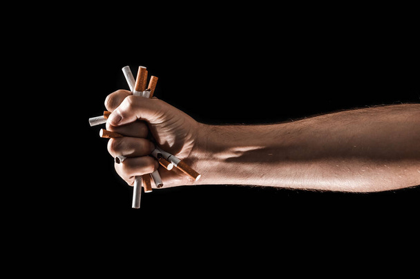 Creative background, male hand clenches a fist of a cigarette. The concept of smoking kills, stop smoking. Copy space. - Foto, afbeelding